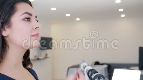 漂亮的女孩在室内镜子特写镜头前的嘴唇上涂化妆品视频的预览图