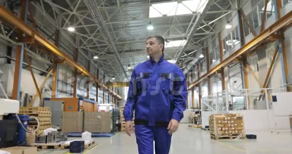穿蓝色制服的工程师正在工厂里行走正面视图视频的预览图