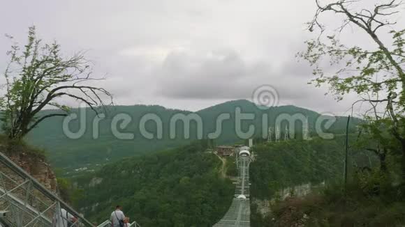 高加索人沿着巨大的钢制悬索桥穿过山峡视频的预览图