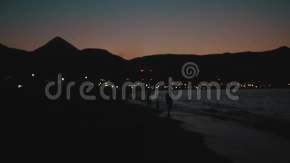 在海边的沙滩上站着一家人天空五彩缤纷视频的预览图