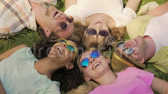 混种女孩和朋友躺在草地上打电话看短信笑着视频的预览图
