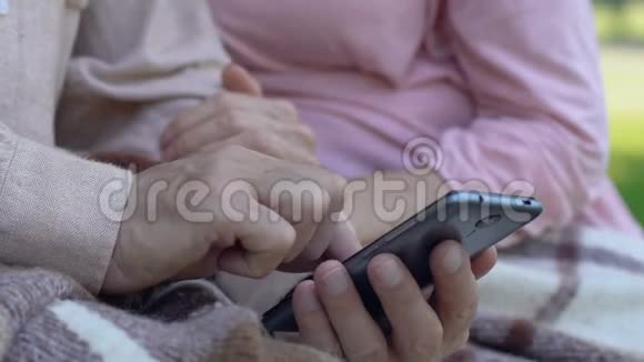 年龄大的男人展示女性在智能手机上容易使用移动应用程序现代技术视频的预览图