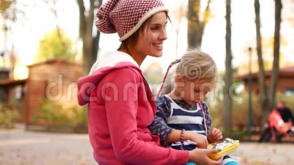 妈妈和女儿在秋天的下午在公园吃午饭爱家庭食物视频的预览图