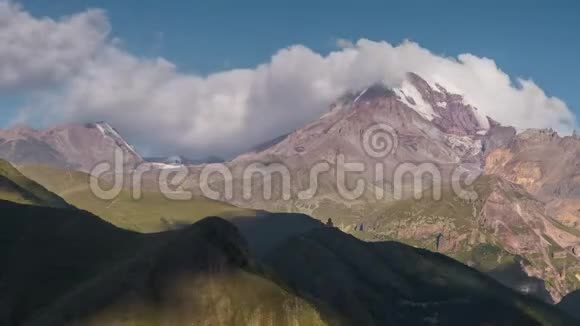 高加索高地古老的教堂和卡兹别克山峰有雪帽阳光和移动的阴影视频的预览图