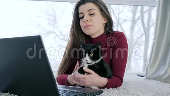 漂亮的女主人和猫在家里躺在电脑前休息视频的预览图