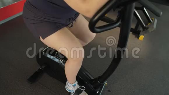 肥胖妇女在体育俱乐部骑固定自行车减肥锻炼视频的预览图