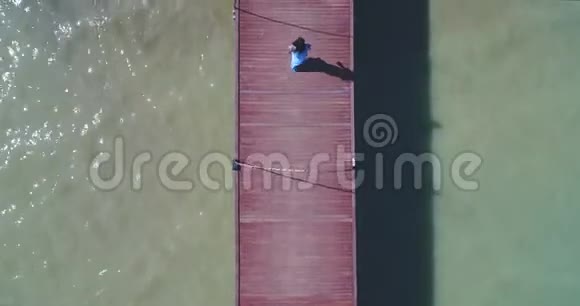 空中一个亚洲女孩走在码头上向海滩走去那里有棕榈树视频的预览图
