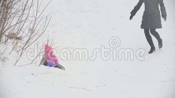 可爱的母亲抱着女儿在冬天的雪地公园散步视频的预览图