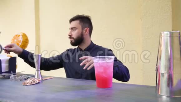 酒吧柜台上漂亮的酒吧服务员用冰做五颜六色的鸡尾酒用餐巾纸擦拭桌子视频的预览图