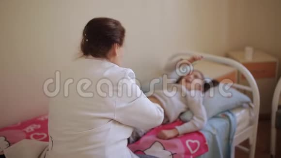 老年妇女按摩师给医院里的小女孩做腹部按摩视频的预览图