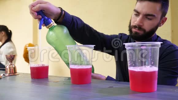 酒吧桌上的大胡子男酒保用塑料眼镜做明亮的饮料视频的预览图