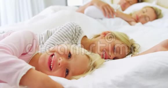 微笑的孩子在床上放松而父母睡在背景4k视频的预览图