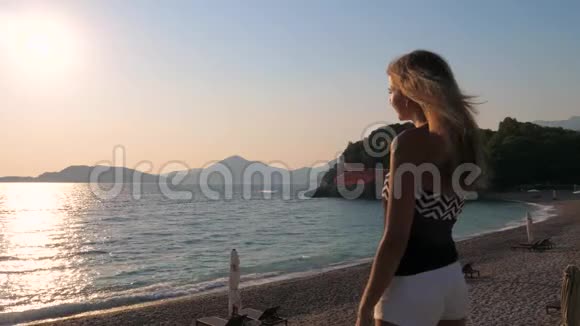 站在沙滩上欣赏日落慢动作的美女视频的预览图