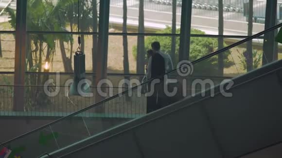 两位商业伙伴在机场乘坐自动扶梯前来开会视频的预览图