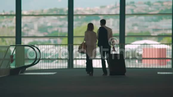 商务旅行男人和女人步行到机场的自动扶梯携带行李视频的预览图