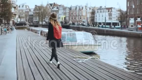 可爱的旅游女性散步在电话里交谈快乐轻松的旅行者沿着河船堤走4K后视图视频的预览图