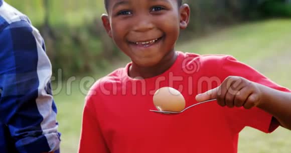 快乐男孩拿着鸡蛋和勺子在后院4k视频的预览图