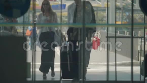 穿着长裙的男人和女人通过自动开门进入机场大厅视频的预览图
