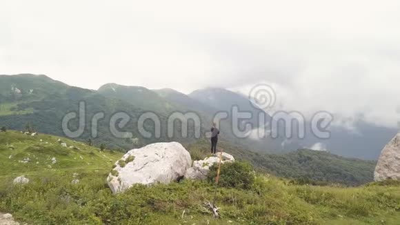 站在山边的大石头上的女人欣赏美丽的景色视频的预览图