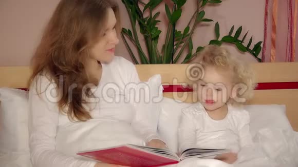 快乐地拥抱着妈妈可爱的女儿睡前看书视频的预览图