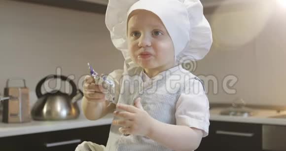 一个有趣的厨师孩子坐在桌子上吃巧克力糖果视频的预览图