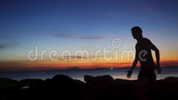 年轻运动员在海滩日落时跑步训练的剪影慢动作1920x1080视频的预览图