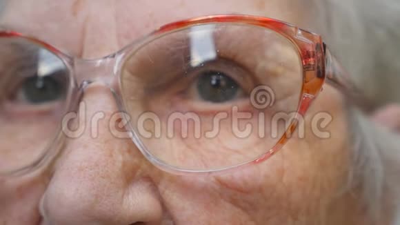老妇人望着远处摘下眼镜奶奶摘下眼镜奶奶的特写肖像视频的预览图