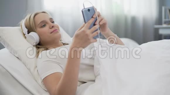 戴耳机的青少年在床上听音乐在社交媒体上交流视频的预览图