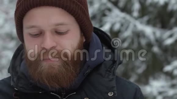在森林里一个戴着帽子和夹克抽着烟的年轻人留着胡子的嬉皮士视频的预览图