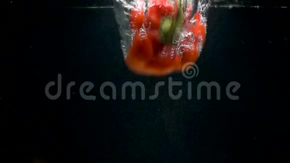 黑色背景下红甜椒在水中落下的视频视频的预览图