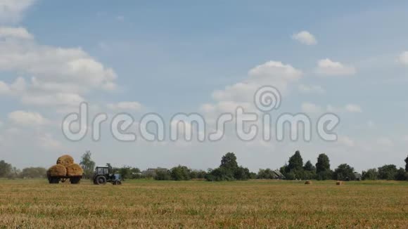 旧拖拉机带着扭曲的稻草捆穿过农田农业视频的预览图