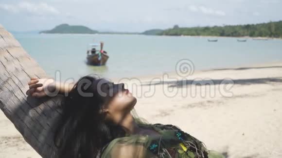 穿着绿色连衣裙的亚洲女孩躺在棕榈树上休息放松视频的预览图