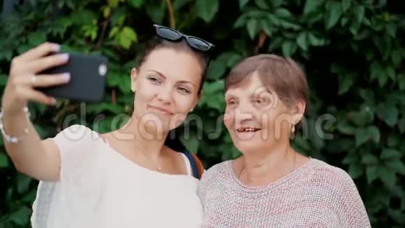 漂亮的老奶奶和她的孙女在户外自拍四处闲逛看着相机笑着笑着视频的预览图