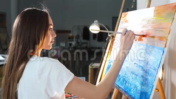 一位女艺术家在车间里用油画颜料在画布上作画视频的预览图