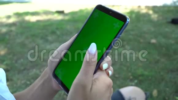 女子手持智能手机绿色屏幕特写色度视频的预览图