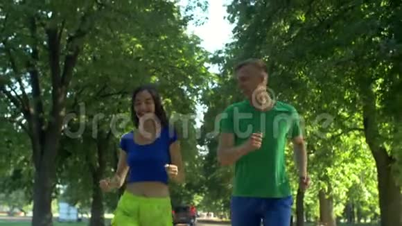 一对活跃的情侣一起在夏季公园慢跑视频的预览图
