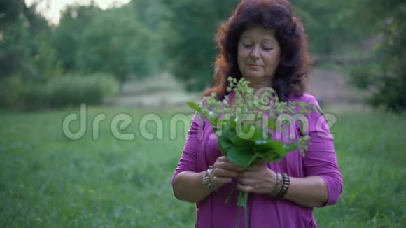 一位老年妇女手持一束野花草地和微笑视频的预览图
