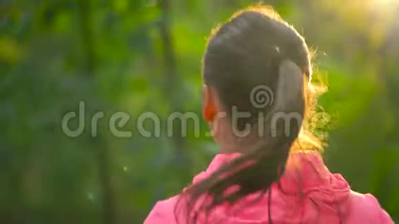日落时分一个女人穿过一个秋天的公园向后看慢动作视频的预览图