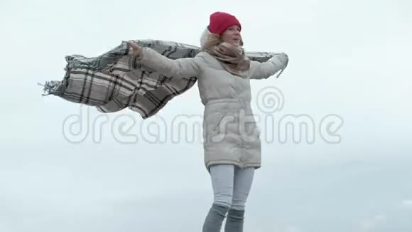 一个穿暖和衣服的年轻女子手里拿着毯子站在天空中视频的预览图