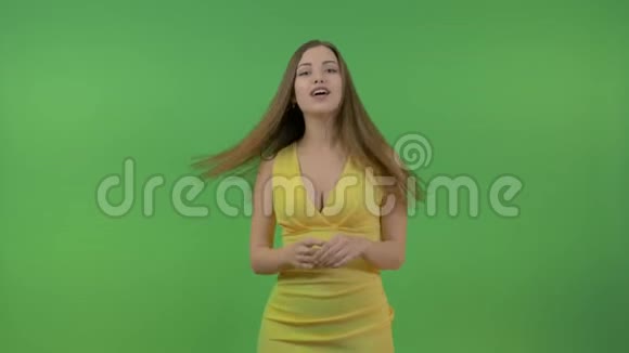 一位穿着黄色连衣裙和长发的年轻美女问了一个问题点击屏幕在绿色的背景上视频的预览图