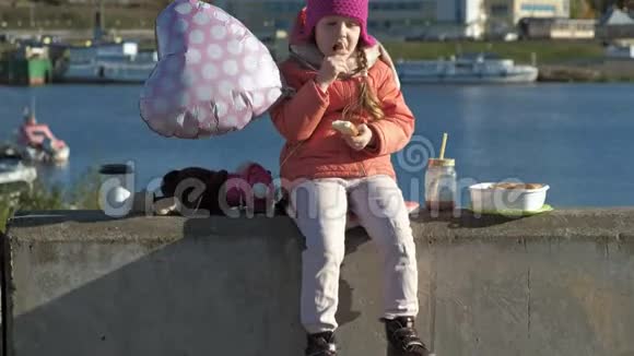 小女孩戴着粉红色的帽子带着气球在河港迪恩斯视频的预览图