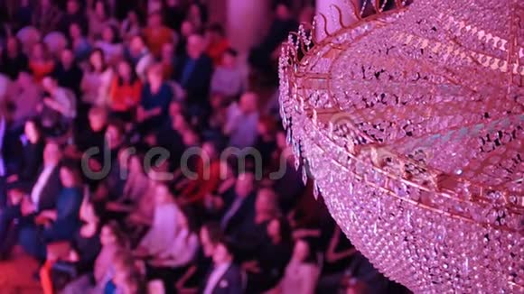 音乐厅的音乐会里面有一个大水晶吊灯坐在椅子上的人视频的预览图