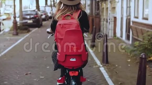 后景骑自行车带红色背包的女性慢动作兴奋的高加索旅游女人生活方式美容博主视频的预览图