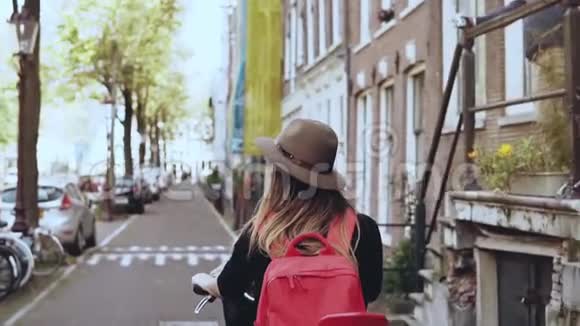 骑自行车的女孩后座是红色的慢动作特写快乐的女游客休闲自行车沿街骑行视频的预览图