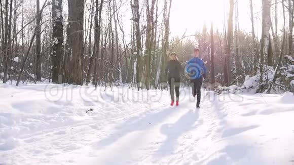 冬季森林在晨公园的小径上奔跑的年轻男女美丽的阳光视频的预览图