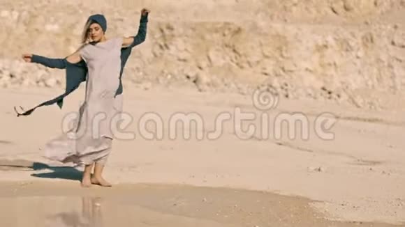 优雅的女孩穿着民族服装在湖边的岩石背景下跳舞视频的预览图