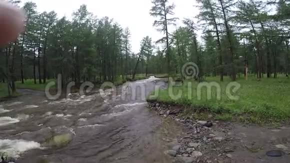 洪水期间在河谷的Sayan山下下了大雨湍急的河床上有一条泥泞的小溪视频的预览图