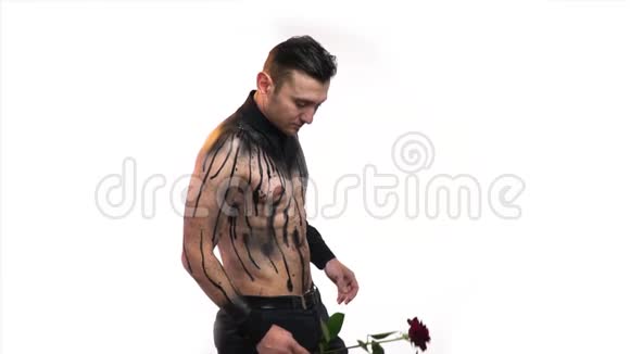 一个肌肉发达的男子在黑色的身体艺术手里拿着一朵红色的玫瑰动作缓慢视频的预览图