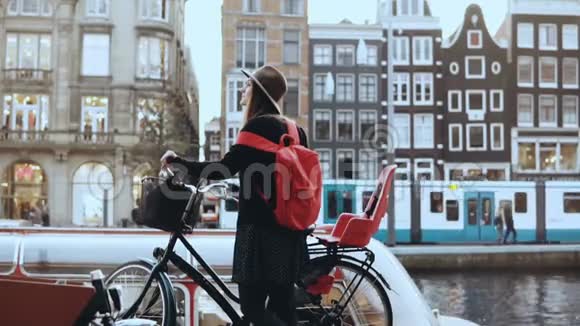 旅游小姐骑自行车离开城市河流码头白人女性站着骑着她的自行车令人惊叹的老城慢动作视频的预览图