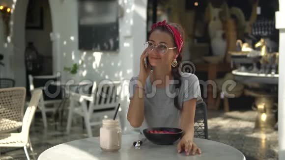 美丽的黑发少女戴着红色的色拉和灰色的茶座坐在户外休息由她说话视频的预览图